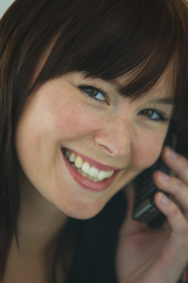 A smiling beautiful young woman on a mobile phone. A smiling beautiful young woman on a mobile phone