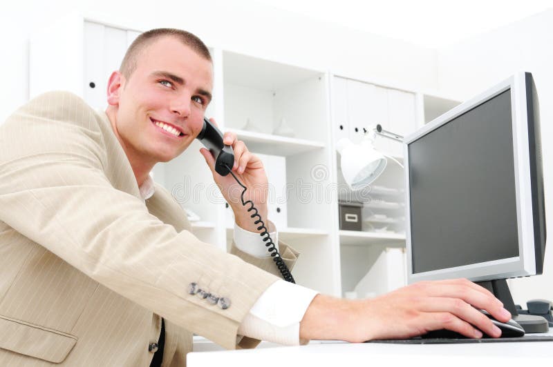 Happy businessman with phone and computer in office. Happy businessman with phone and computer in office