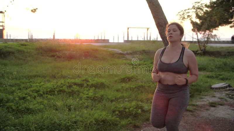 телопозитивная плюс женская спортсменка, бегающая в солнечном парке. концепция потери веса и активный образ жизни