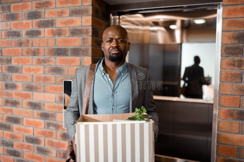 Темнокожий работник офиса покидая офис после прекращения работника стоковое изображение