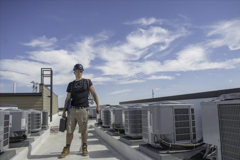Техник Hvac рядом с конденсаторами стоковая фотография Техник Hvac рядом с конденсаторами стоковая фотография