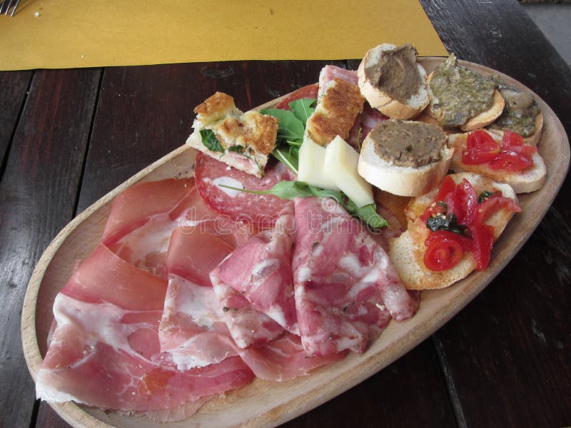 Типичная деревенская тосканская закуска с crostini, ветчиной, кабаниной, салями, сыром на деревянном подносе итальянский стартер стоковые изображения rf Типичная деревенская тосканская закуска с crostini, ветчиной, кабаниной, салями, сыром на деревянном подносе итальянский стартер стоковые изображения rf