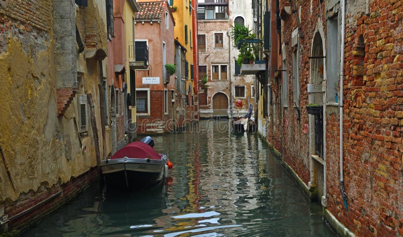Тихий канал в Венеции с на лодках и стенами рушиться.