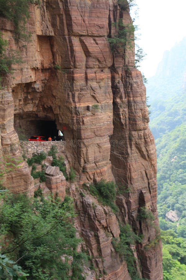 The Guoliang Tunnel is carved along the side of and through a mountain in China. The tunnel is located in the Taihang Mountains which are situated in the Henan Province of China. Photos of the road are often misidentified as photos of the Road of Death in Bolivia. Before the tunnel was constructed, access to the nearby Guoliang village was limited to a difficult path carved into the mountainside. The village is nestled in a valley surrounded by towering mountains cut off from civilization. In 1972 a group of villagers led by Shen Mingxin decided to carve a road into the side of the mountain. They raised money to purchase hammers and steel tools. Thirteen villagers began the project. The tunnel is 1.2 kilometres (0.75 mi) long, 5 metres (16 ft) tall and 4 metres (13 ft) wide. Some of the villagers died in accidents during construction. On 1 May 1977 the tunnel was opened to traffic. The Guoliang Tunnel is carved along the side of and through a mountain in China. The tunnel is located in the Taihang Mountains which are situated in the Henan Province of China. Photos of the road are often misidentified as photos of the Road of Death in Bolivia. Before the tunnel was constructed, access to the nearby Guoliang village was limited to a difficult path carved into the mountainside. The village is nestled in a valley surrounded by towering mountains cut off from civilization. In 1972 a group of villagers led by Shen Mingxin decided to carve a road into the side of the mountain. They raised money to purchase hammers and steel tools. Thirteen villagers began the project. The tunnel is 1.2 kilometres (0.75 mi) long, 5 metres (16 ft) tall and 4 metres (13 ft) wide. Some of the villagers died in accidents during construction. On 1 May 1977 the tunnel was opened to traffic.