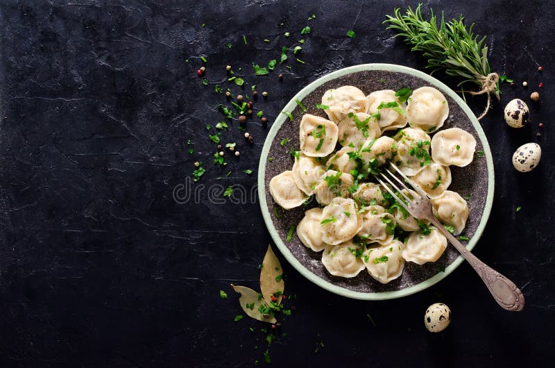 Традиционное русское pelmeni, равиоли, вареники с мясом на черной конкретной предпосылке Петрушка, яичка триперсток, перец стоковые изображения Традиционное русское pelmeni, равиоли, вареники с мясом на черной конкретной предпосылке Петрушка, яичка триперсток, перец стоковые изображения