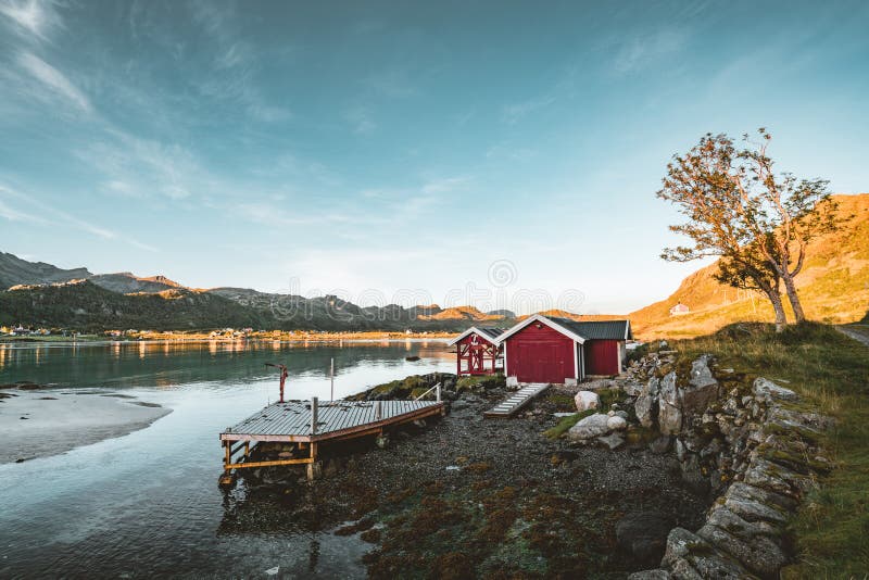 Традиционный красный дом fishin в Bjoernsand около Reine в Lofoten, Норвегии с красными домами rorbu После полудня захода солнца стоковые фотографии rf Традиционный красный дом fishin в Bjoernsand около Reine в Lofoten, Норвегии с красными домами rorbu После полудня захода солнца стоковые фотографии rf
