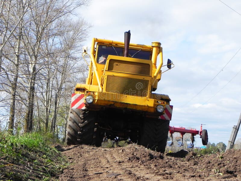 Трактор вспахивает поле в лете Редакционное Стоковое Изображение ...