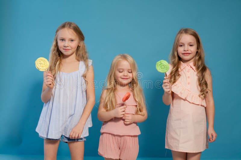 Три модные маленькие девочки едят конфеты стоковая фотография