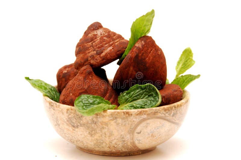 Chocolate truffles and mint leaves in a round marble bowl, isolated on white background. Chocolate truffles and mint leaves in a round marble bowl, isolated on white background