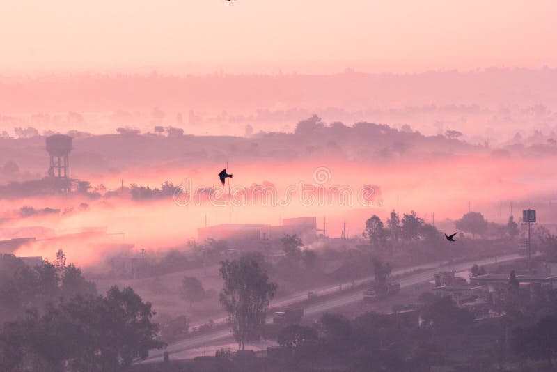 A winter morning in some small city of Rajasthan, with first ray of light the fog is visible. The yellow color and dusty looking mountains makes if more mysterious place. A winter morning in some small city of Rajasthan, with first ray of light the fog is visible. The yellow color and dusty looking mountains makes if more mysterious place