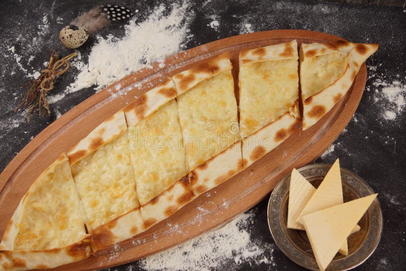Турецкая пицца вызвана pide Блюдо с Pide с сыром на темной таблице, взбрызнутой с мукой стоковая фотография Турецкая пицца вызвана pide Блюдо с Pide с сыром на темной таблице, взбрызнутой с мукой стоковая фотография