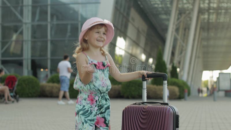 Турист девушки ребенка с сумкой чемодана, недалеко от аэропорта. Парень с танцами багажа радуется большие пальцы шоу вверх сток-видео
