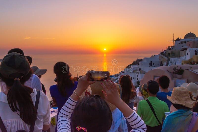 Туристское принимая изображение красивого захода солнца в Santorini, Греции стоковое изображение rf Туристское принимая изображение красивого захода солнца в Santorini, Греции стоковое изображение rf