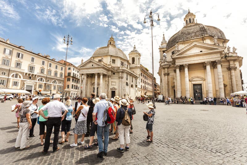 Group of tourists with tour guide in Piazza del Popolo (Peoples Square) in Rome, Italy. A crowd of tourists stops in the famous square. Piazza del Popolo is a large urban square in Rome. In the background the Twin churches. Santa Maria in Montesanto (left, built 1662-75) and Santa Maria dei Miracoli (right, built 1675-79). Concept of holiday and traveling. Group of tourists with tour guide in Piazza del Popolo (Peoples Square) in Rome, Italy. A crowd of tourists stops in the famous square. Piazza del Popolo is a large urban square in Rome. In the background the Twin churches. Santa Maria in Montesanto (left, built 1662-75) and Santa Maria dei Miracoli (right, built 1675-79). Concept of holiday and traveling.