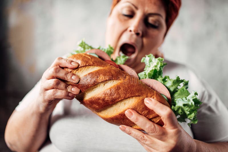 Тучная женщина ест сандвич, полный и bulimic стоковые фотографии rf Тучная женщина ест сандвич, полный и bulimic стоковые фотографии rf