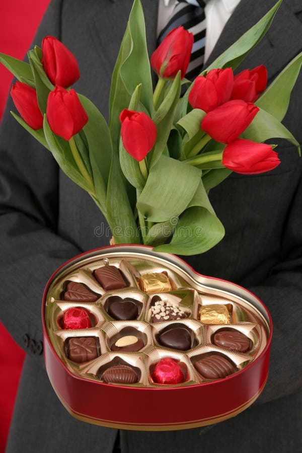 Man Holding Heart Shaped Box of Candy and Red Tulips. Man Holding Heart Shaped Box of Candy and Red Tulips