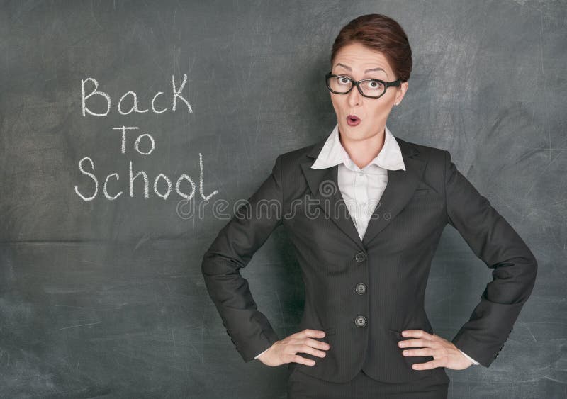 Surprised teacher on the school blackboard background with phrase Back to school. Surprised teacher on the school blackboard background with phrase Back to school