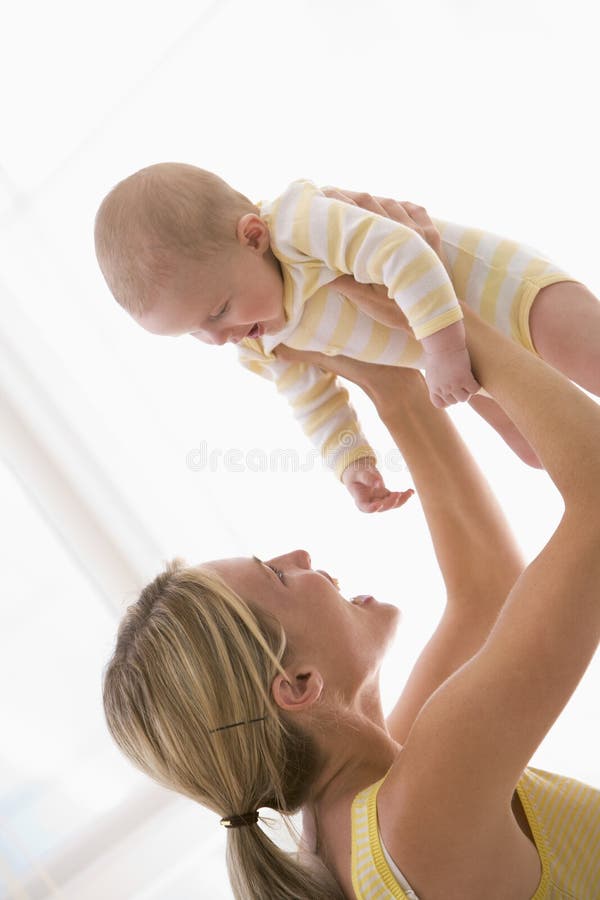 Mother holding baby indoors smiling. Mother holding baby indoors smiling