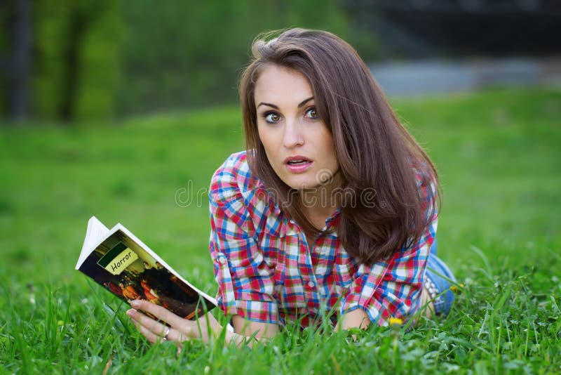 Young girl looking shocked while reading a horror book. Young girl looking shocked while reading a horror book