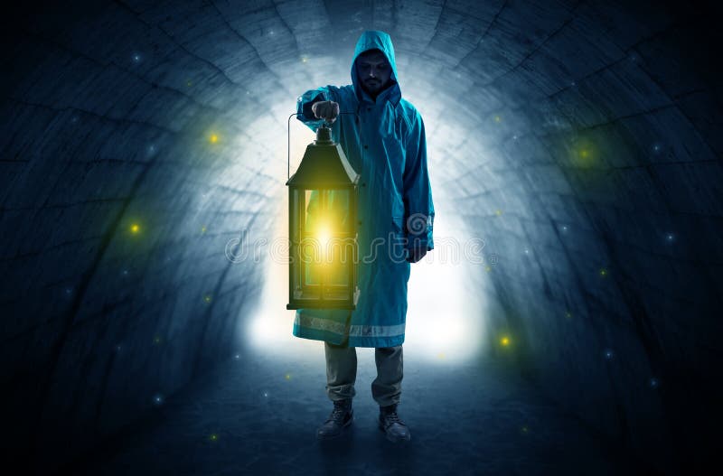 Ugly man in raincoat walking with glowing lantern in a dark tunnel. Ugly man in raincoat walking with glowing lantern in a dark tunnel