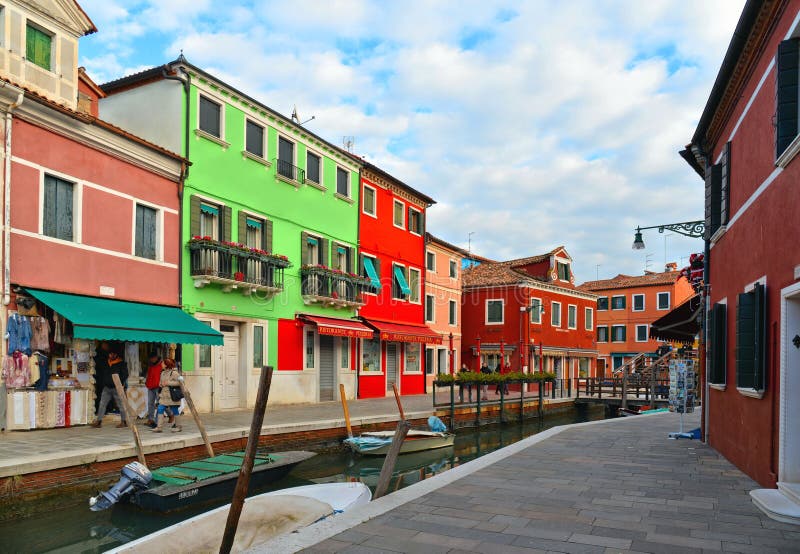 Улица острова Burano живописная с небольшими покрашенными домами в строке, канале со шлюпками fishermans, пасмурном голубом небе стоковое фото Улица острова Burano живописная с небольшими покрашенными домами в строке, канале со шлюпками fishermans, пасмурном голубом небе стоковое фото