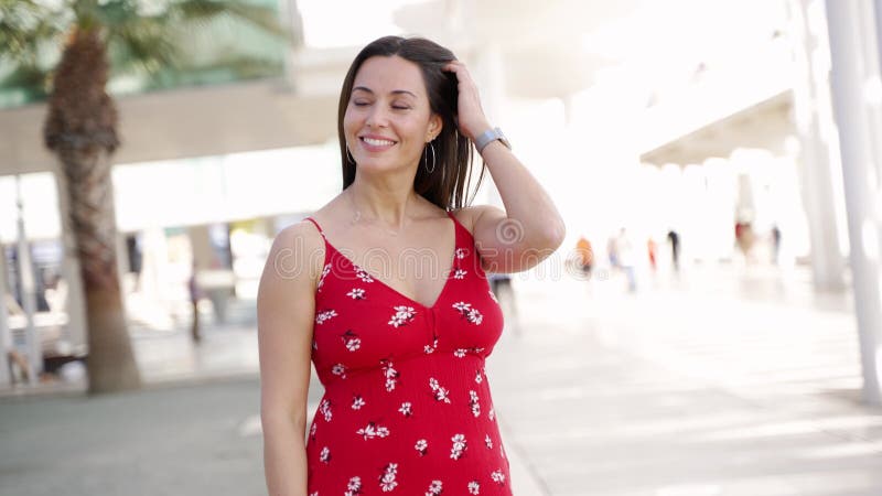 улыбающаяся женщина в модном платье гуляет по улице и смотрит на камеру видеоматериал