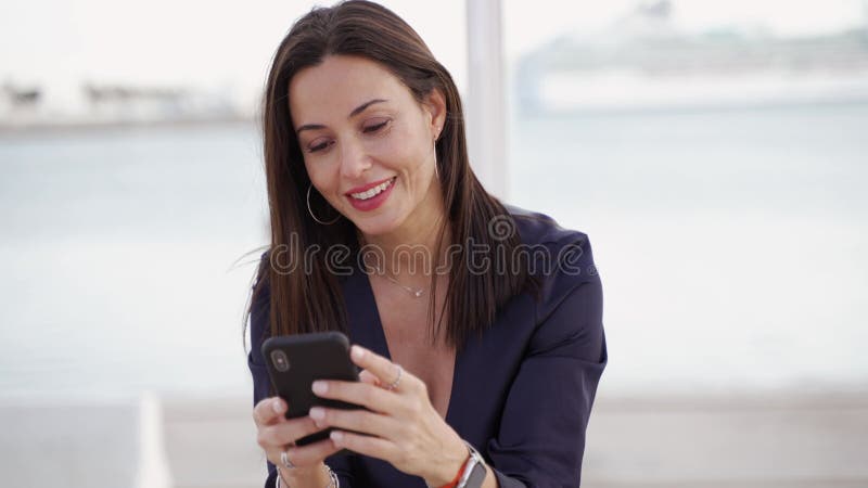 улыбающаяся женщина, использующая смартфон на улице акции видеоматериалы