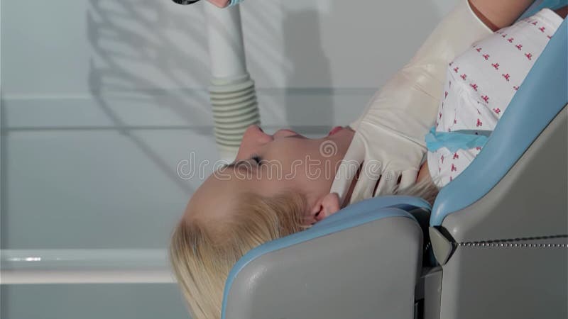 Улыбающаяся женщина-стоматолог осматривает рот пациента в ярком стоматологическом кабинете акции видеоматериалы