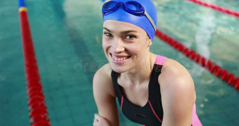 Улыбающаяся пловчиха, сидящая у бассейна сток-видео
