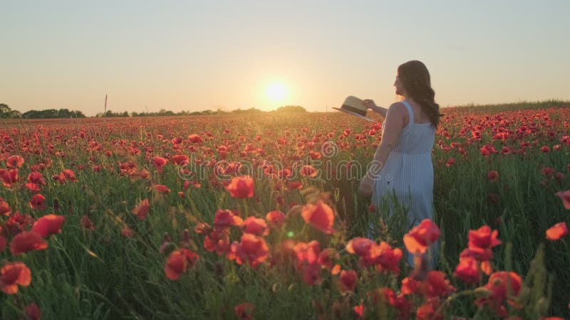 Улыбаясь, женщина с танцами шляпы в цветущий луг