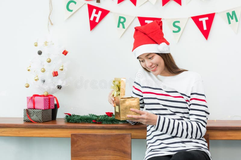Улыбка женщины Азии когда открытая подарочная коробка xmas золота на партии праздника w стоковое изображение rf Улыбка женщины Азии когда открытая подарочная коробка xmas золота на партии праздника w стоковое изображение rf