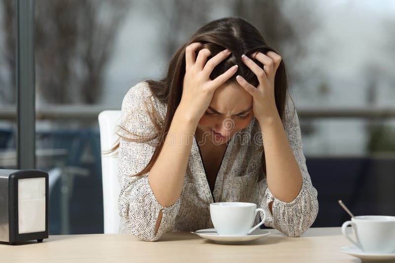 Sad and depressed woman alone in a lonely bar after a break up with a rainy winter day outdoor in the background. Sad and depressed woman alone in a lonely bar after a break up with a rainy winter day outdoor in the background