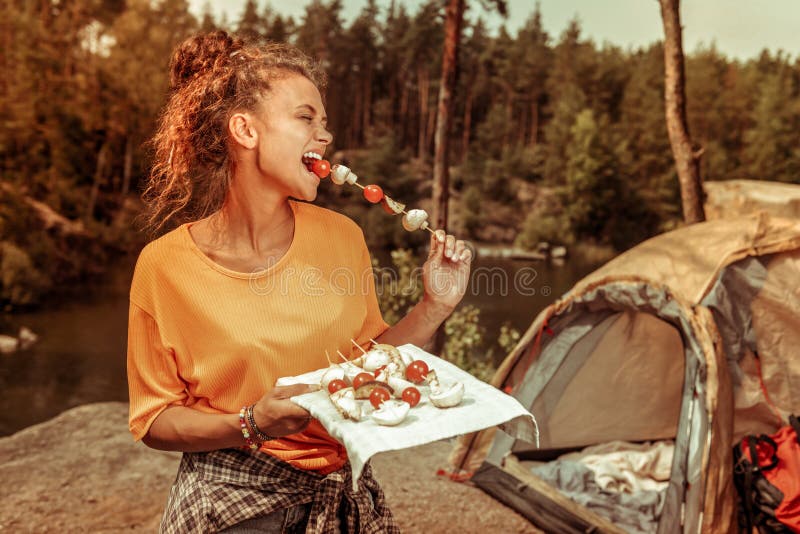 Услаженная счастливая женщина пробуя вкусный томат стоковые изображения rf Услаженная счастливая женщина пробуя вкусный томат стоковые изображения rf