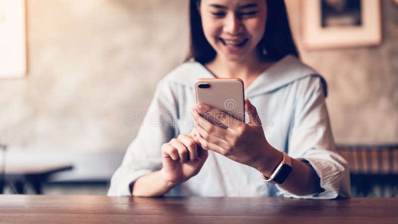 Усмехаться азиатской женщины используя смартфон отправляя SMS на кафе космос экземпляра для объявлений стоковая фотография Усмехаться азиатской женщины используя смартфон отправляя SMS на кафе космос экземпляра для объявлений стоковая фотография