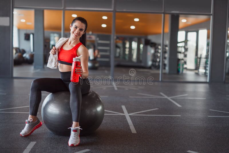 Усмехаясь sportive женщина сидя на шарике медицины стоковое фото Усмехаясь sportive женщина сидя на шарике медицины стоковое фото