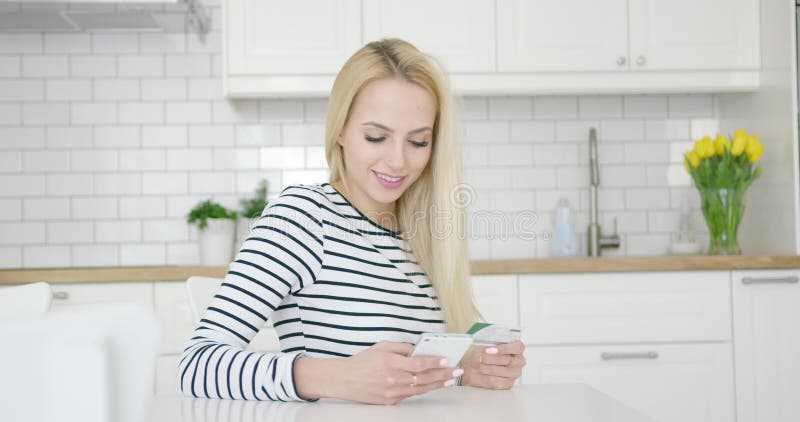 Усмехаясь женщина используя кредитную карточку и телефон акции видеоматериалы