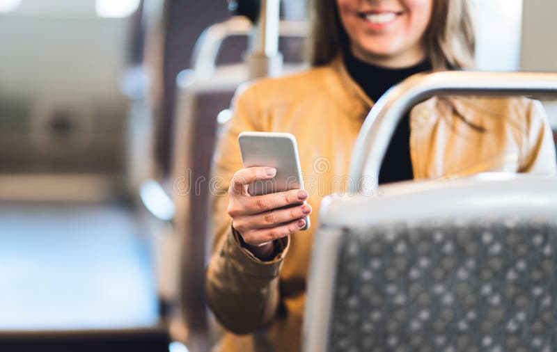 Усмехаясь женщина используя smartphone в поезде, метро, шине или трамвае стоковые фото