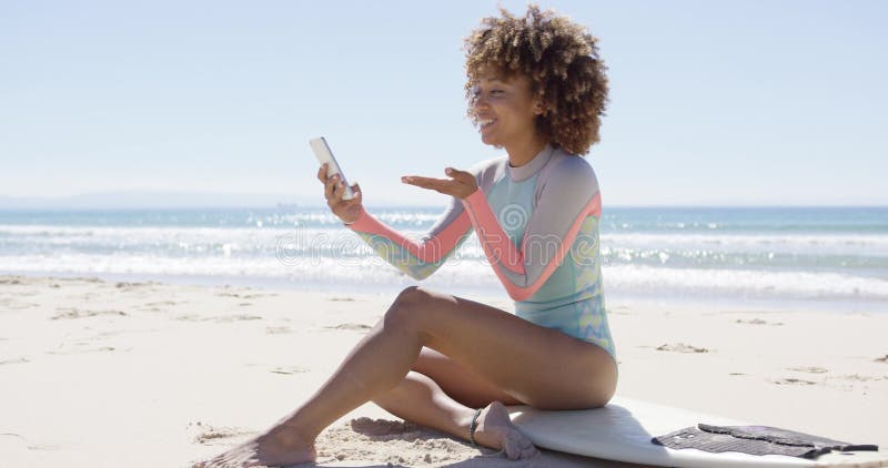 Усмехаясь женщина на пляже используя smartphone сток-видео