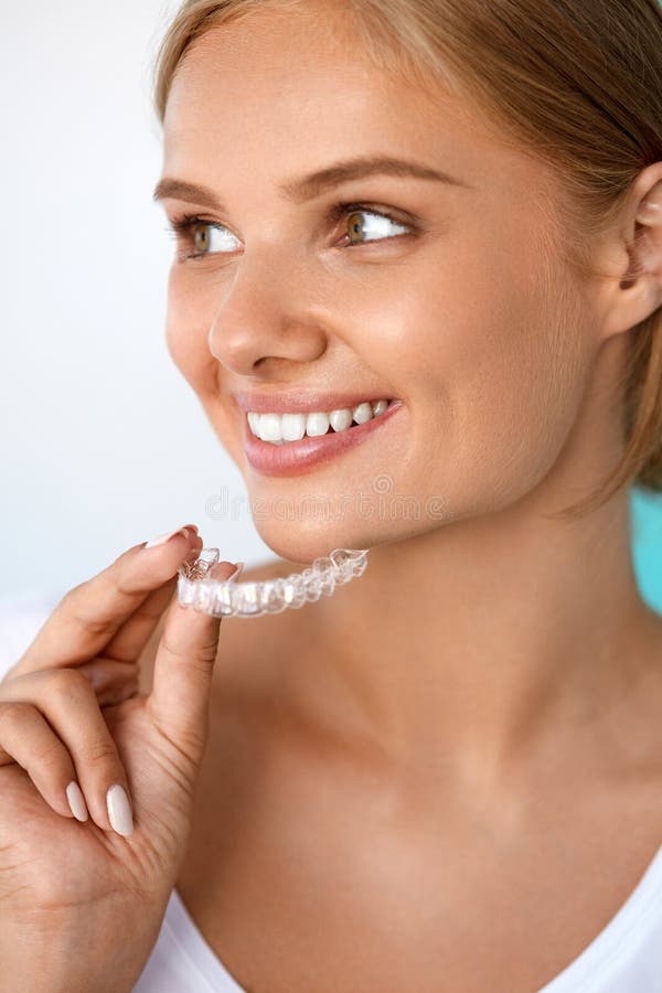 Teeth Whitening. Beautiful Smiling Woman With White Smile, Straight Teeth Using Teeth Whitening Tray. Girl Holding Invisible Braces, Teeth Trainer. Dental Treatment Concept. High Resolution Image. Teeth Whitening. Beautiful Smiling Woman With White Smile, Straight Teeth Using Teeth Whitening Tray. Girl Holding Invisible Braces, Teeth Trainer. Dental Treatment Concept. High Resolution Image