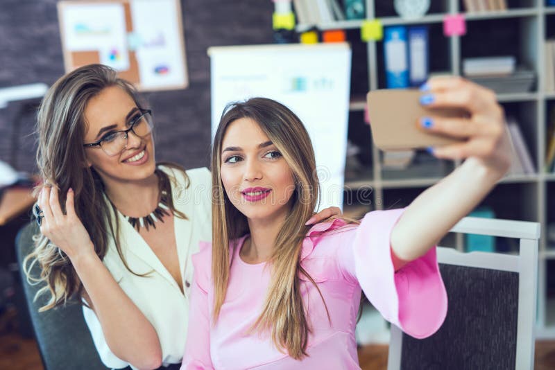 Усмехаясь жизнерадостные бизнес-леди принимая selfie стоковые изображения Усмехаясь жизнерадостные бизнес-леди принимая selfie стоковые изображения