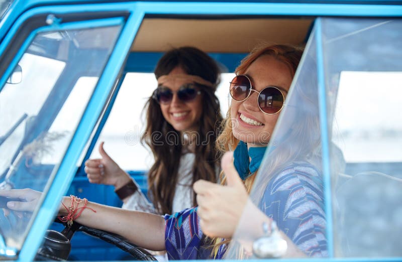 Усмехаясь молодые женщины hippie управляя автомобилем минифургона стоковая фотография