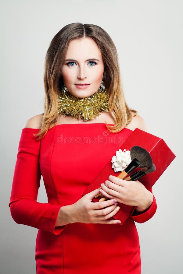 Усмехаясь фотомодель женщины в красном платье с подарочной коробкой рождества стоковое изображение Усмехаясь фотомодель женщины в красном платье с подарочной коробкой рождества стоковое изображение