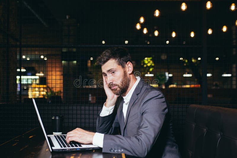 успешный бизнесмен, работающий на ноутбуке во время обеденного перерыва, сидящий в ресторане отеля, устал выполнять задачи стоковое фото rf