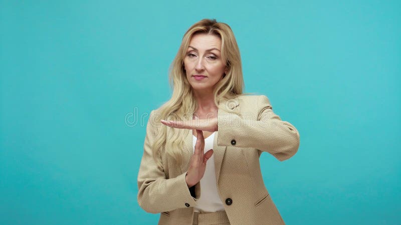 Устала средняя достигшая возраста женщина в деловом костюме, жест время на камеру с исчерпаны расстроенным крайнего срока представ сток-видео