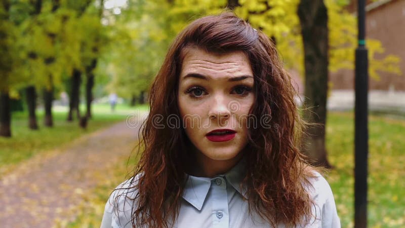 Устрашенная молодая женщина redhead в парке видеоматериал