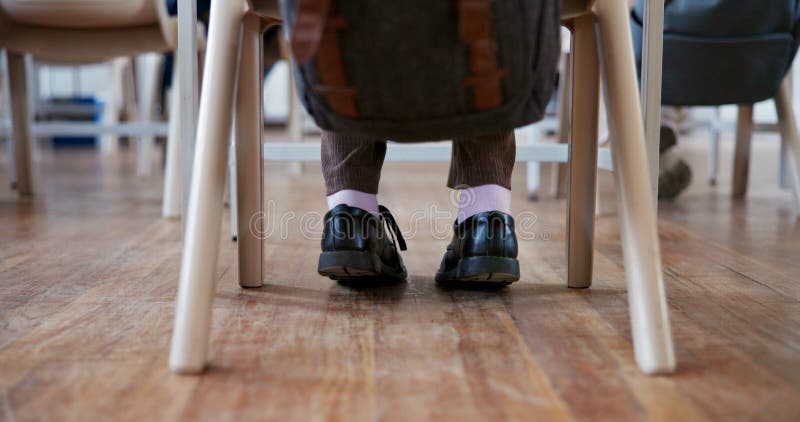 ученик и ступни в классе для обучения с ботинками рюкзак и изучения за партой. человек стоковое изображение rf
