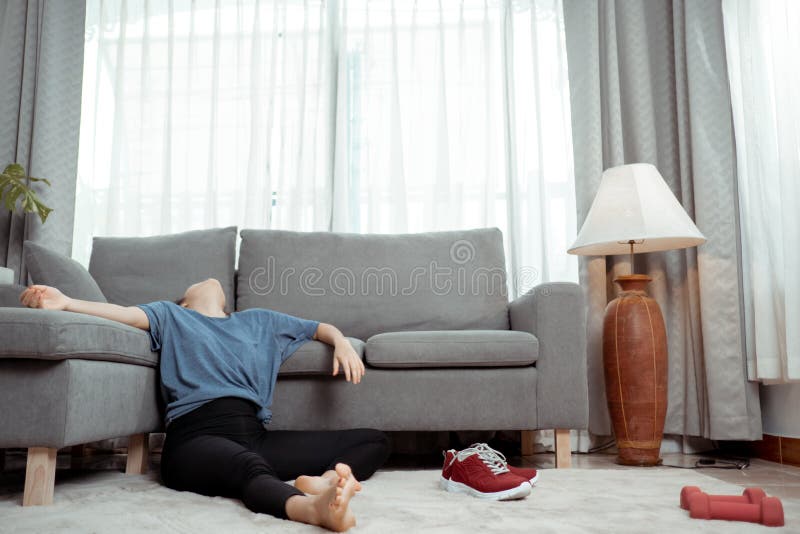 Молодая спортивная азиатка, уставшая от спортивных упражнений, сидит на полу между подходами стоковые изображения rf