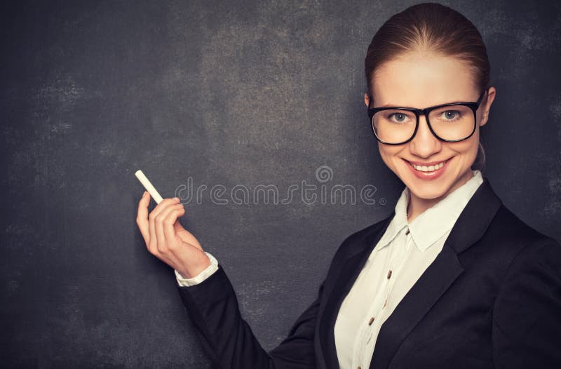 Business woman teacher with glasses and a suit with chalk the lost in thought at a school board. Business woman teacher with glasses and a suit with chalk the lost in thought at a school board