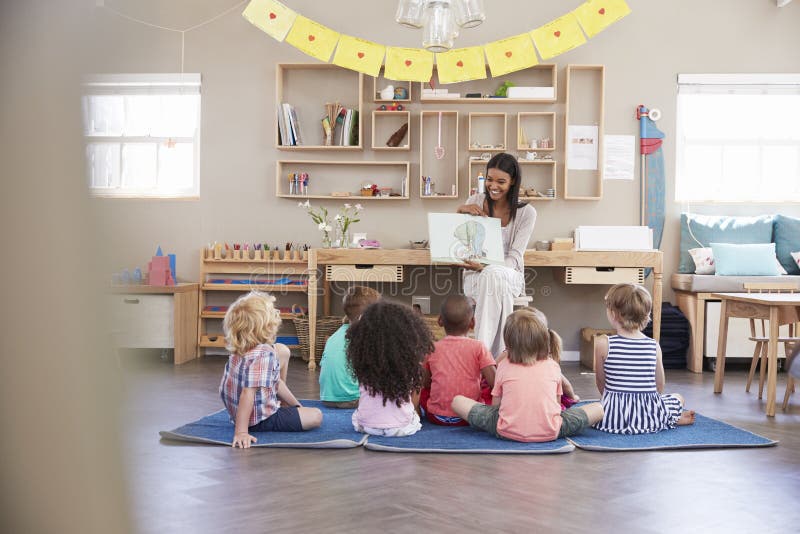 Учитель на школе Montessori читая к детям на времени рассказа стоковое изображение Учитель на школе Montessori читая к детям на времени рассказа стоковое изображение