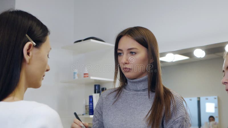 учитель макияжа со своим учеником. урок макияжа в школе красоты. класс master. студент делает макияж модели акции видеоматериалы